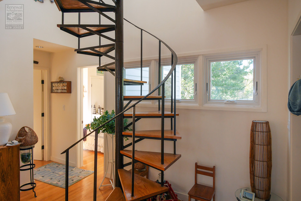 This is an example of a medium sized nautical wood spiral metal railing staircase in Newark with metal risers.