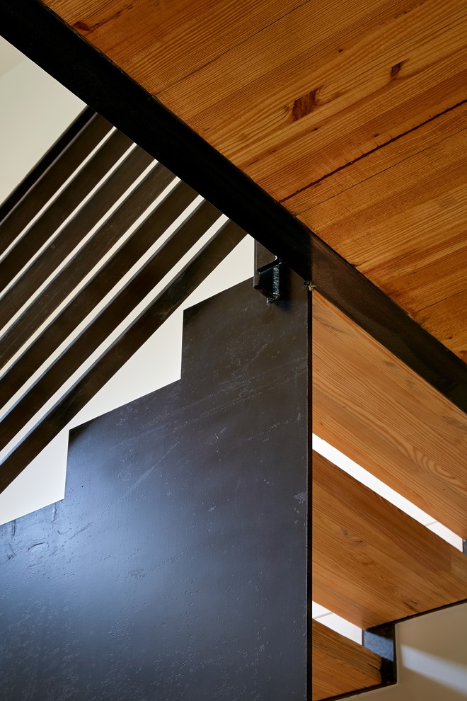 Cette photo montre un escalier moderne en U de taille moyenne avec des marches en bois et un garde-corps en métal.