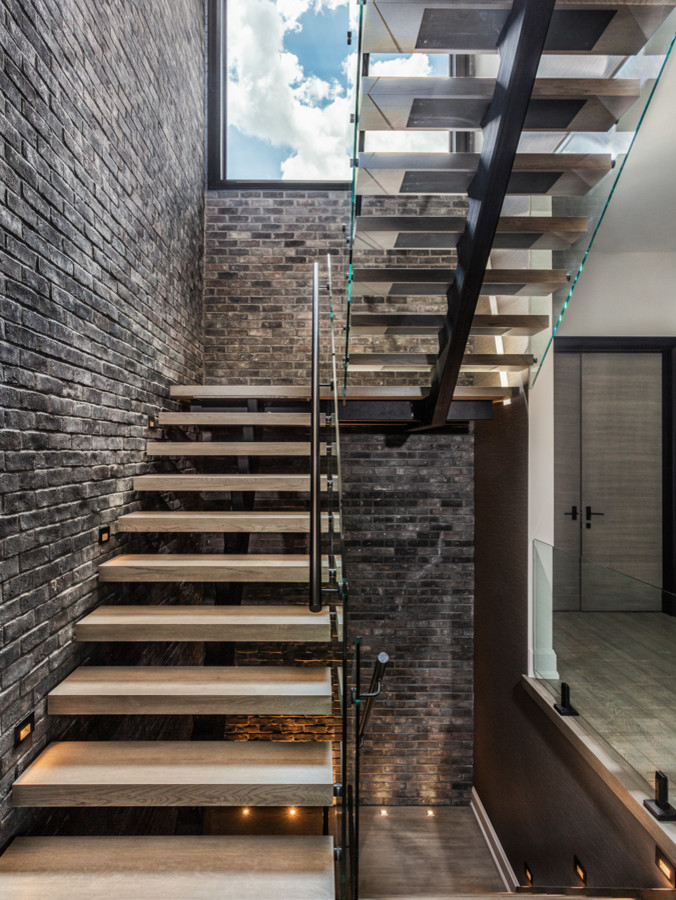 Ejemplo de escalera en U urbana grande sin contrahuella con escalones de madera y barandilla de vidrio
