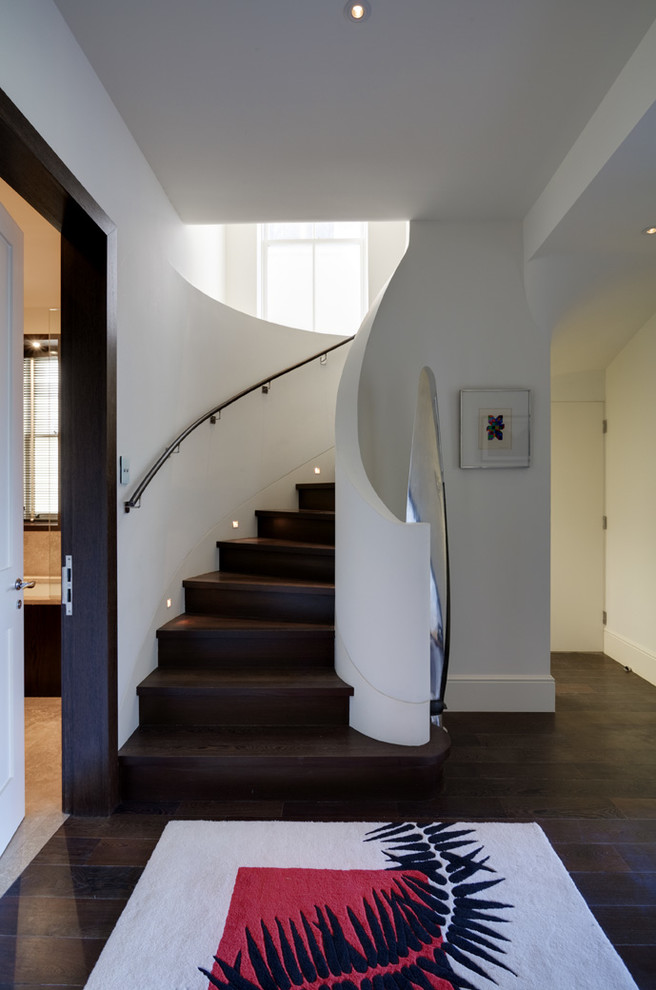 Réalisation d'un escalier courbe design de taille moyenne avec des marches en bois, des contremarches en bois, un garde-corps en matériaux mixtes et éclairage.