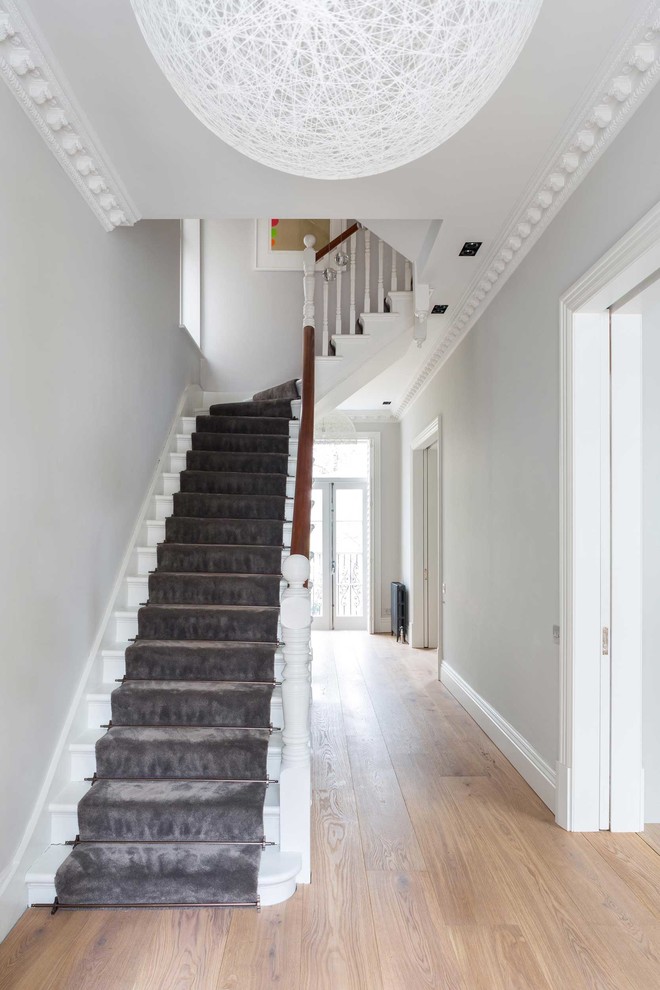 This is an example of a large modern carpeted curved staircase in London with carpeted risers.