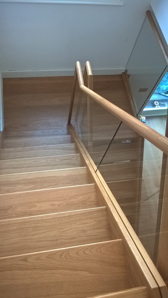 Cette image montre un grand escalier flottant design avec des marches en bois et des contremarches en verre.