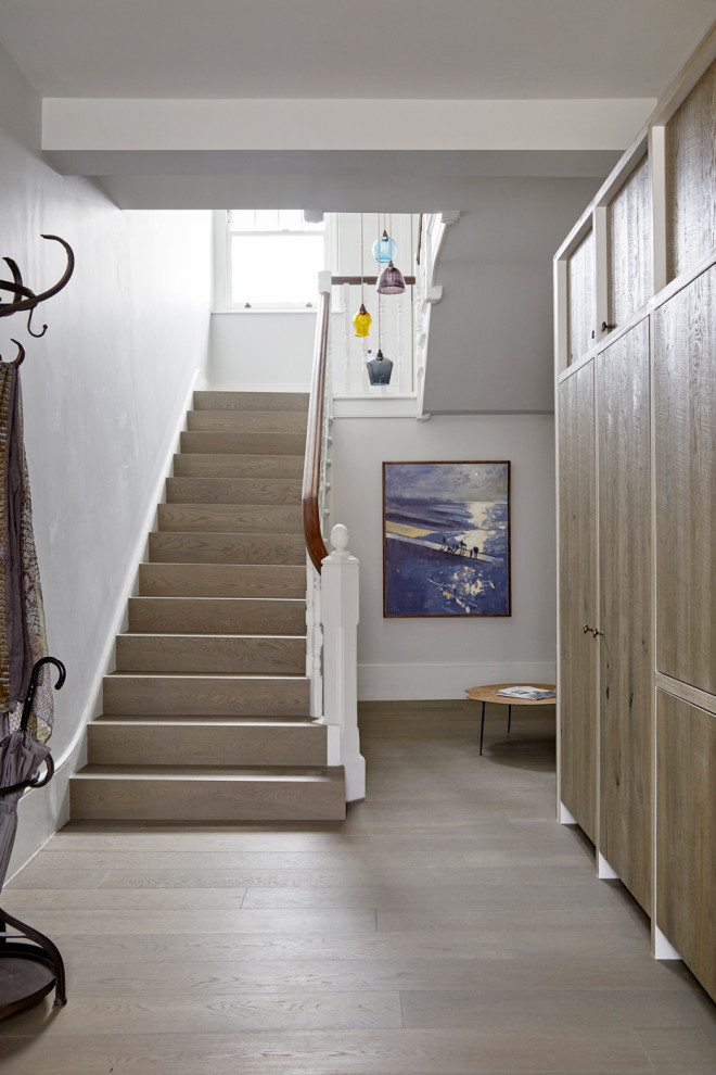 ロンドンにある高級な広いラスティックスタイルのおしゃれな折り返し階段 (木の蹴込み板、木材の手すり) の写真