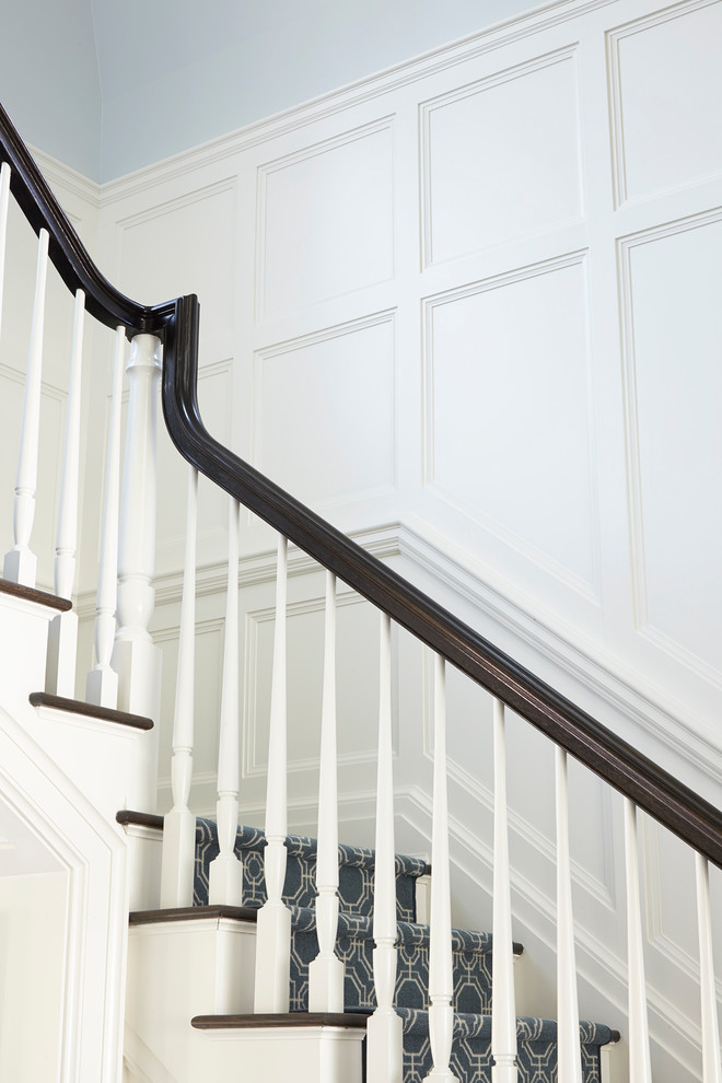 Diseño de escalera en L clásica grande con escalones enmoquetados, contrahuellas enmoquetadas y barandilla de madera