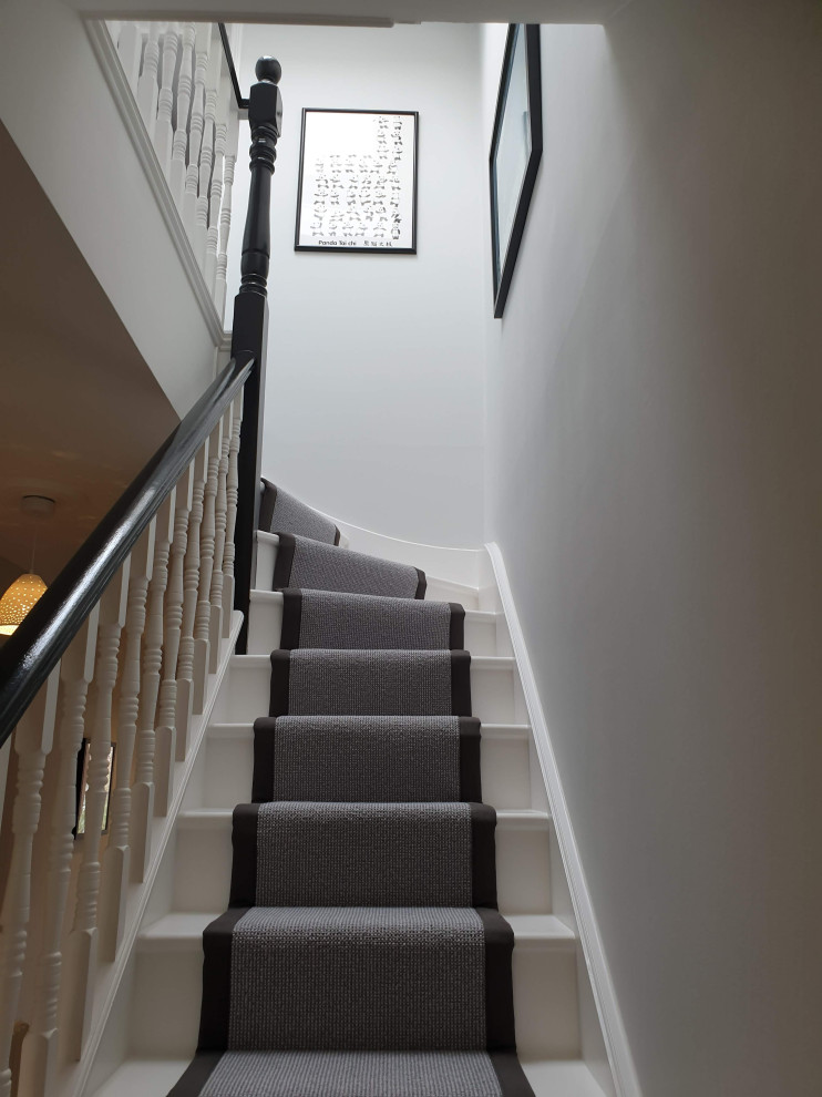 Photo of a large traditional carpeted curved wood railing staircase in London with carpeted risers.