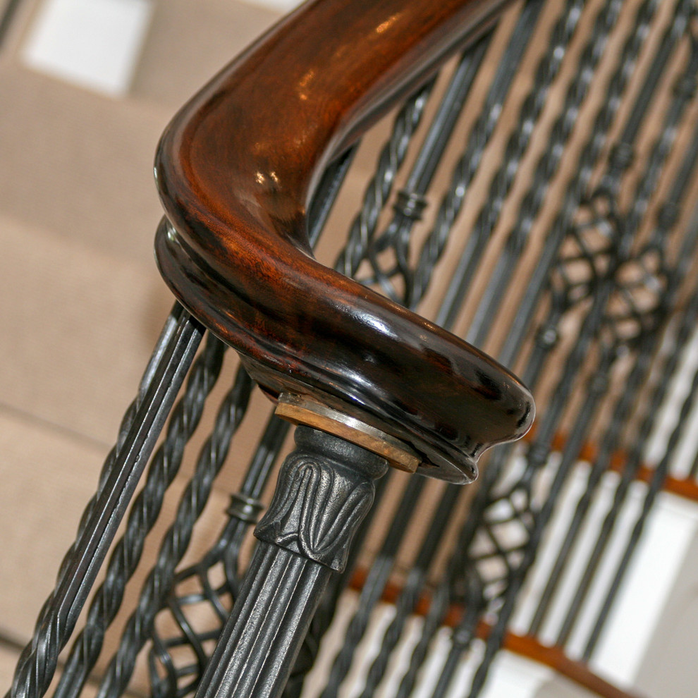 Foto di una grande scala curva tradizionale con pedata in legno, alzata in legno e parapetto in metallo