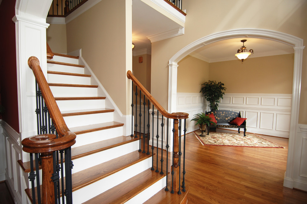 Aménagement d'un grand escalier peint classique en L avec des marches en bois et un garde-corps en matériaux mixtes.