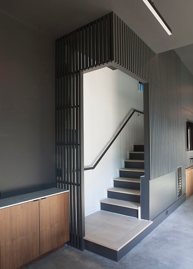 Imagen de escalera recta minimalista con escalones de madera, contrahuellas de madera, barandilla de madera y panelado