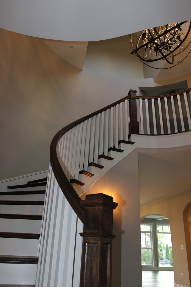 Idée de décoration pour un grand escalier peint courbe craftsman avec des marches en bois et un garde-corps en bois.