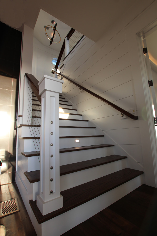 Large classic wood u-shaped wire cable railing staircase in Wilmington with wood risers.