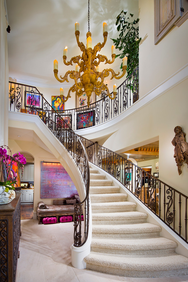 Стильный дизайн: огромная изогнутая лестница в средиземноморском стиле с ступенями с ковровым покрытием и ковровыми подступенками - последний тренд