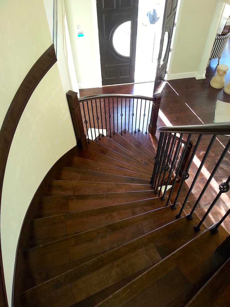 Стильный дизайн: большая изогнутая деревянная лестница в стиле модернизм с деревянными ступенями и деревянными перилами - последний тренд