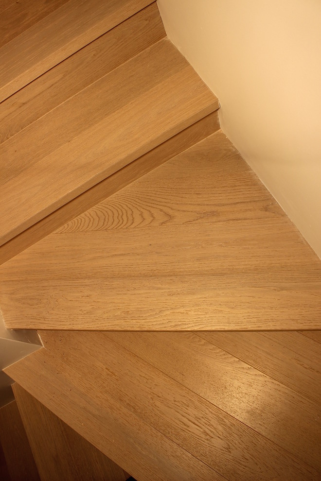 Immagine di una piccola scala curva minimalista con pedata in legno, alzata in legno e parapetto in legno