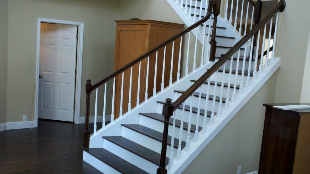 Cette image montre un grand escalier peint traditionnel en L avec des marches en bois.