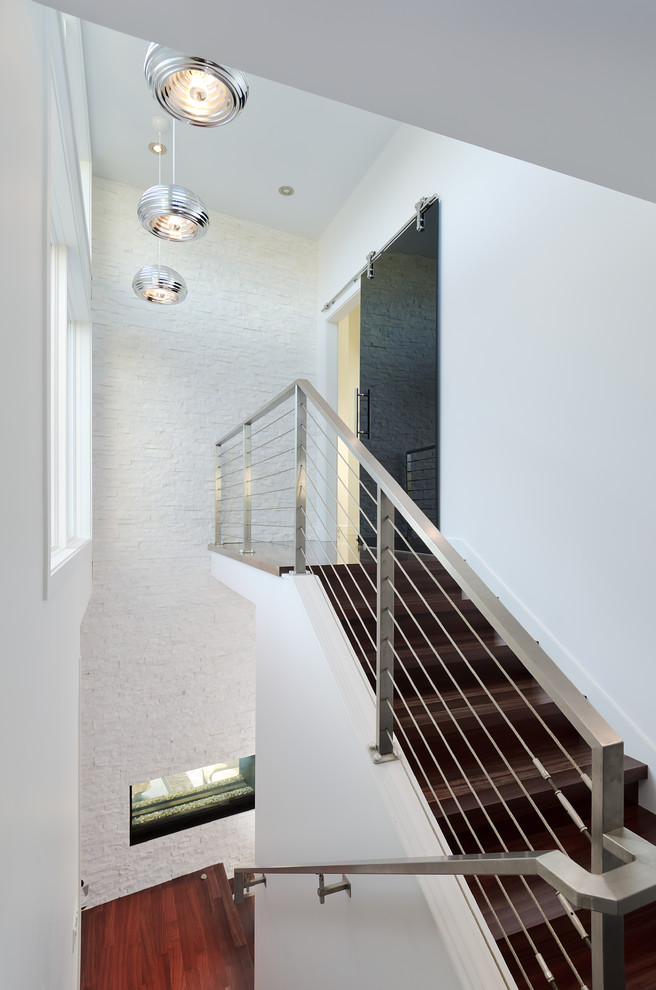 Diseño de escalera contemporánea con escalones de madera, contrahuellas de madera y barandilla de cable