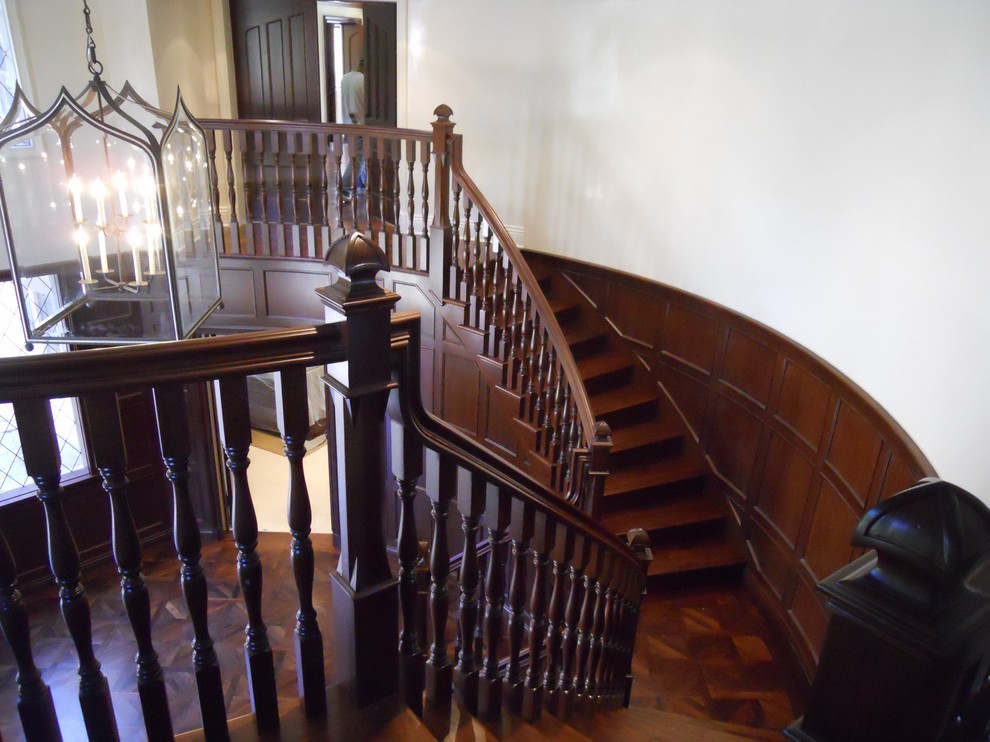 Идея дизайна: огромная изогнутая деревянная лестница в классическом стиле с деревянными ступенями