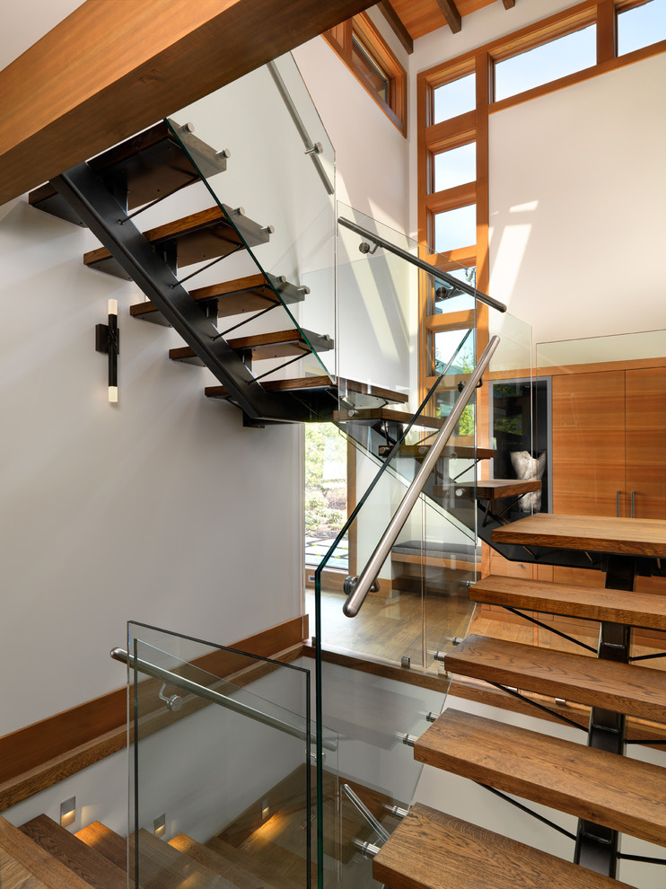 Imagen de escalera suspendida rural sin contrahuella con escalones de madera y barandilla de vidrio