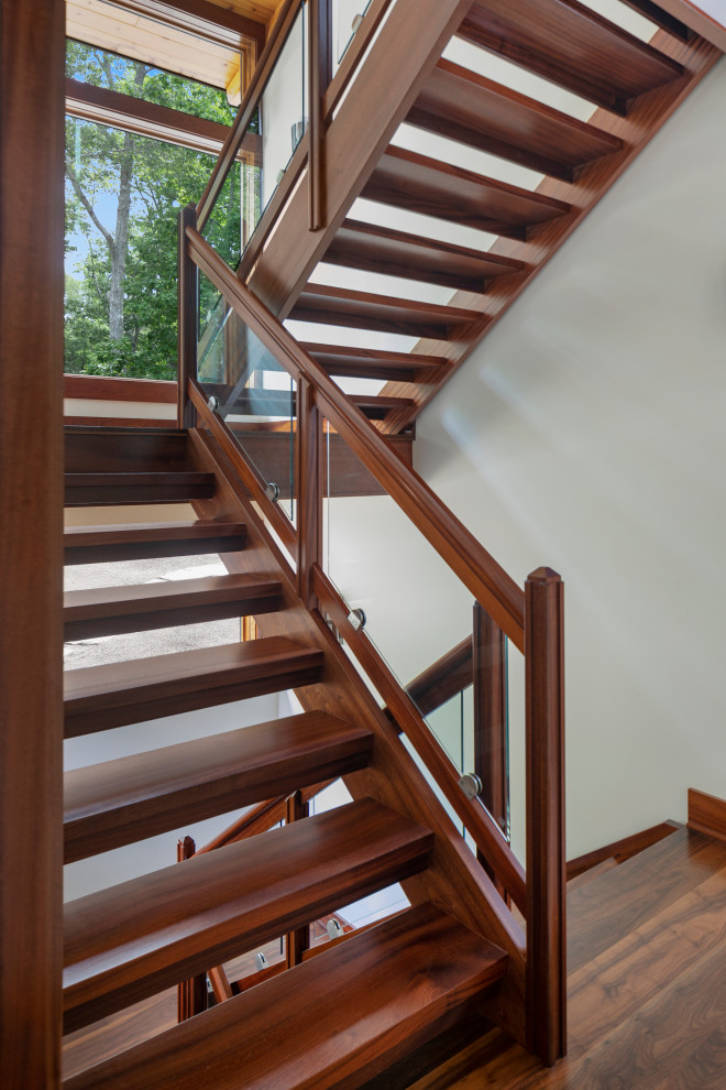 Aménagement d'un grand escalier sans contremarche contemporain en U avec des marches en bois et un garde-corps en verre.