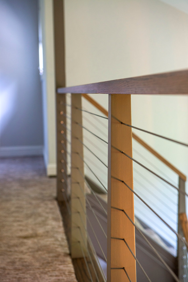 Inspiration pour un grand escalier peint minimaliste en L avec des marches en moquette et un garde-corps en bois.