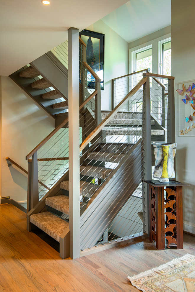 Идея дизайна: большая угловая лестница в стиле модернизм с ступенями с ковровым покрытием, крашенными деревянными подступенками и деревянными перилами