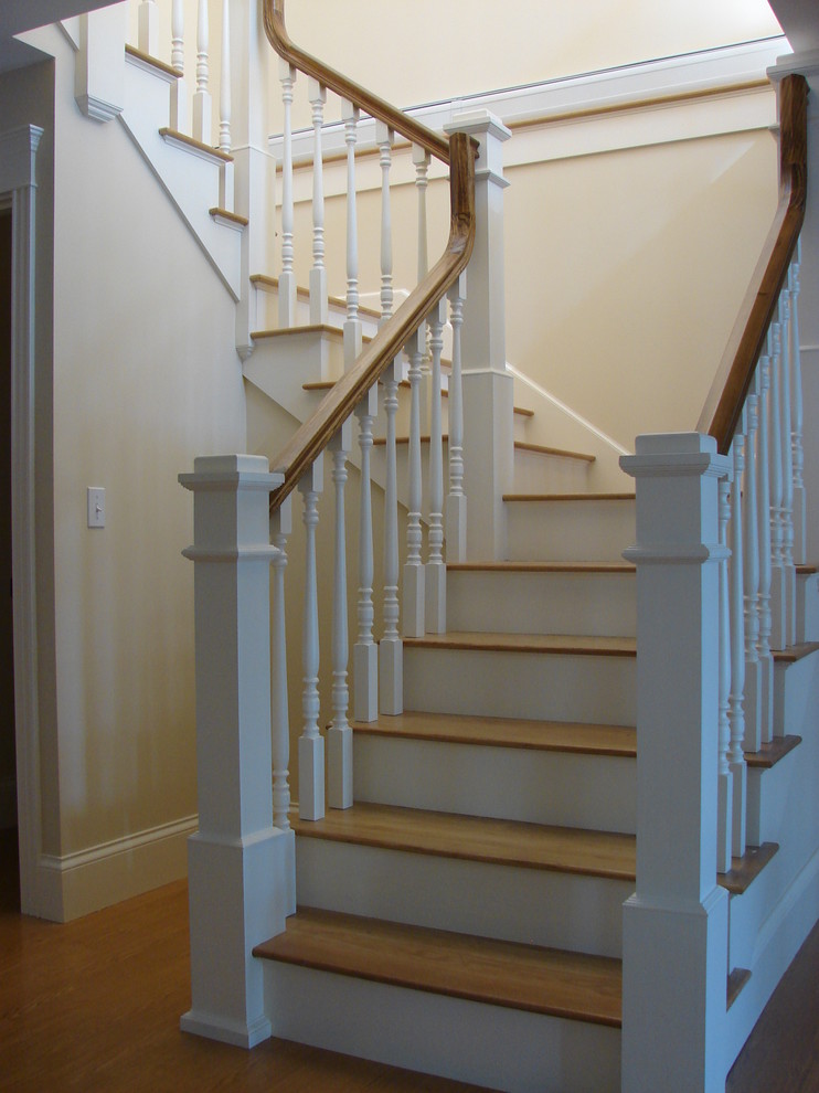 Large traditional wood u-shaped staircase in Portland Maine with painted wood risers.