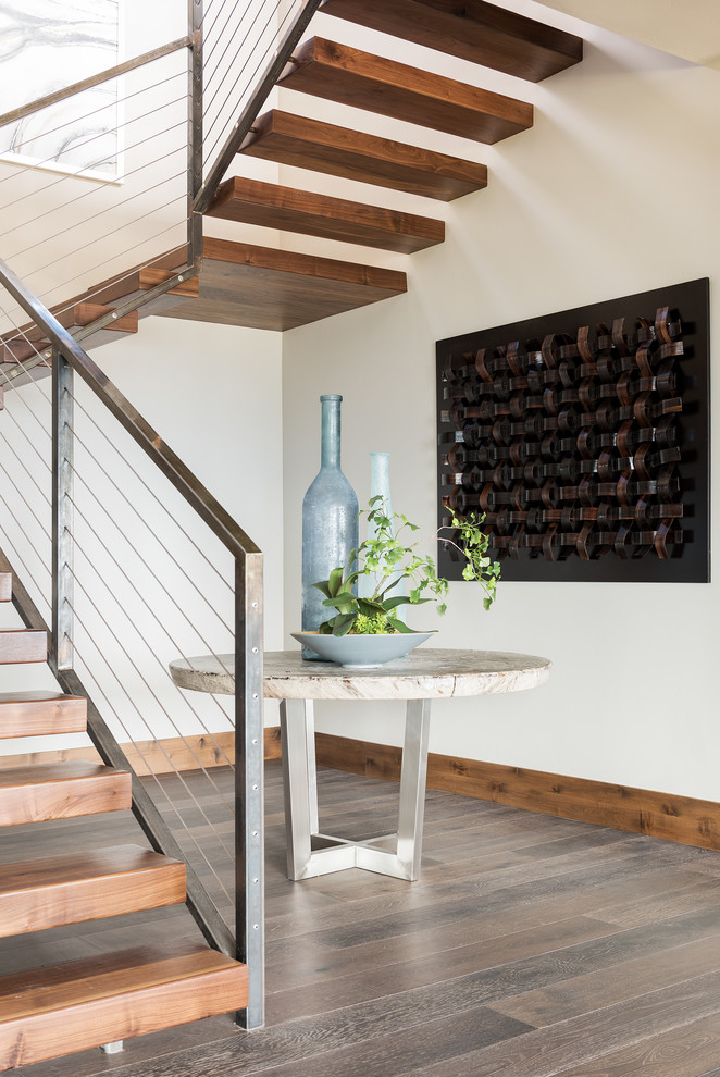 Rustic wood floating wire cable railing staircase in Salt Lake City with open risers and under stair storage.