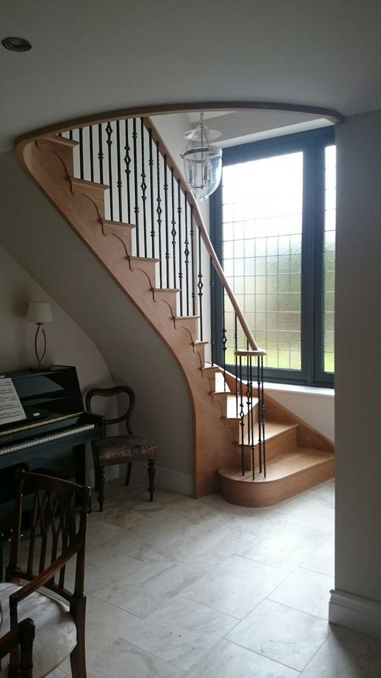 Design ideas for a medium sized classic wood curved metal railing staircase in Cheshire with wood risers.