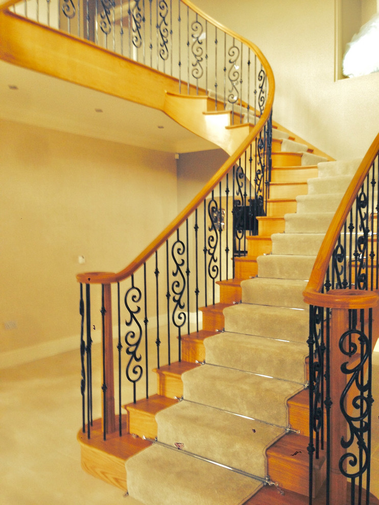 Idée de décoration pour un grand escalier courbe champêtre avec des marches en bois, des contremarches en bois et un garde-corps en métal.
