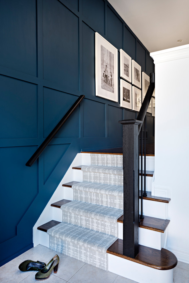 На фото: лестница в стиле неоклассика (современная классика) с ступенями с ковровым покрытием, ковровыми подступенками, металлическими перилами и панелями на части стены
