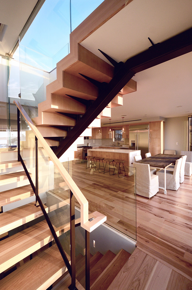 Cette image montre un escalier sans contremarche design en U avec des marches en bois et un garde-corps en verre.