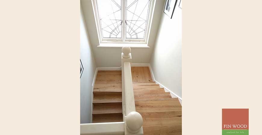 ロンドンにある広いミッドセンチュリースタイルのおしゃれな折り返し階段 (木の蹴込み板) の写真