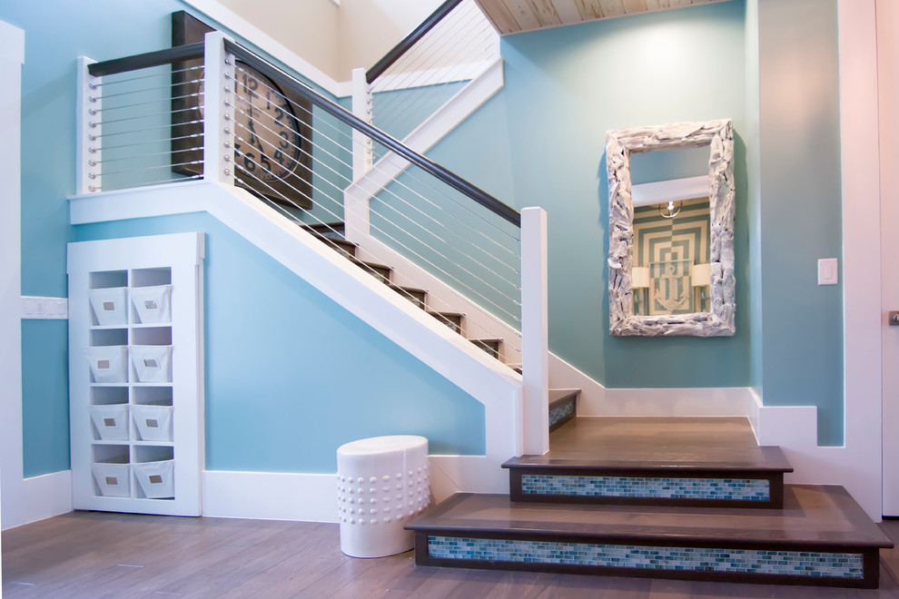 Diseño de escalera en U tropical grande con escalones de madera, contrahuellas con baldosas y/o azulejos y barandilla de cable