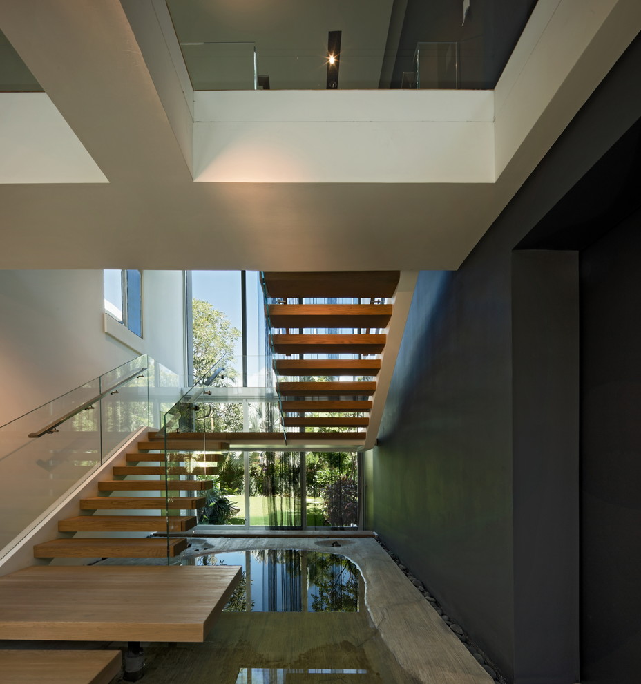 Свежая идея для дизайна: большая п-образная лестница в стиле модернизм с деревянными ступенями и стеклянными перилами без подступенок - отличное фото интерьера