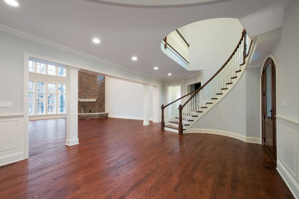 Huge transitional wooden curved wood railing staircase photo in Chicago with painted risers