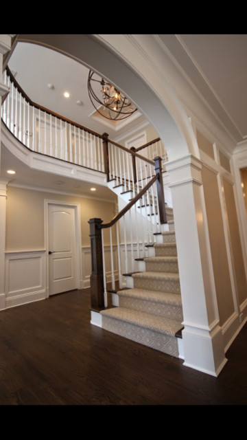 На фото: большая угловая лестница в стиле неоклассика (современная классика) с ступенями с ковровым покрытием и ковровыми подступенками