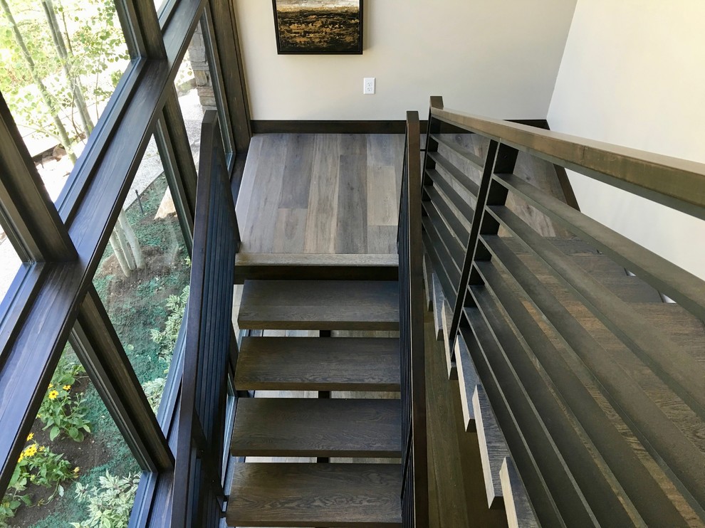 Exemple d'un grand escalier flottant tendance avec des marches en bois, des contremarches en métal et un garde-corps en métal.