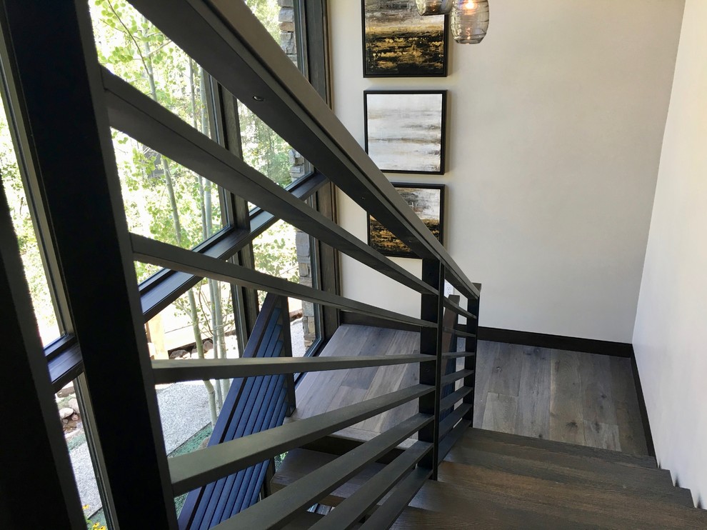 Diseño de escalera suspendida contemporánea grande con escalones de madera, contrahuellas de metal y barandilla de metal