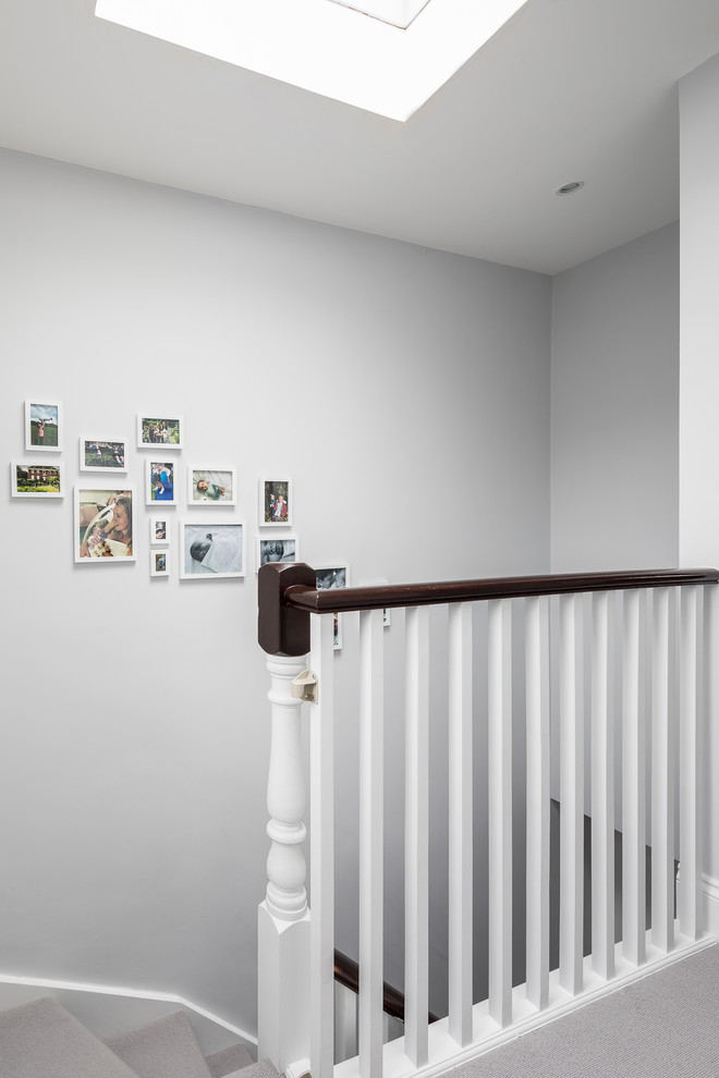 Mid-sized elegant carpeted curved wood railing staircase photo in London with carpeted risers