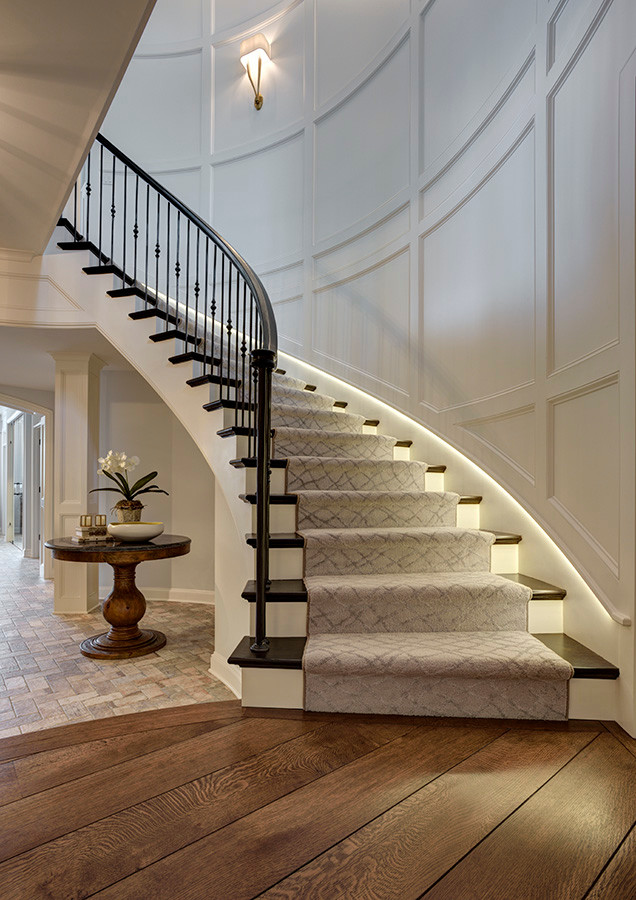 Свежая идея для дизайна: огромная изогнутая деревянная лестница в классическом стиле с деревянными ступенями и перилами из смешанных материалов - отличное фото интерьера