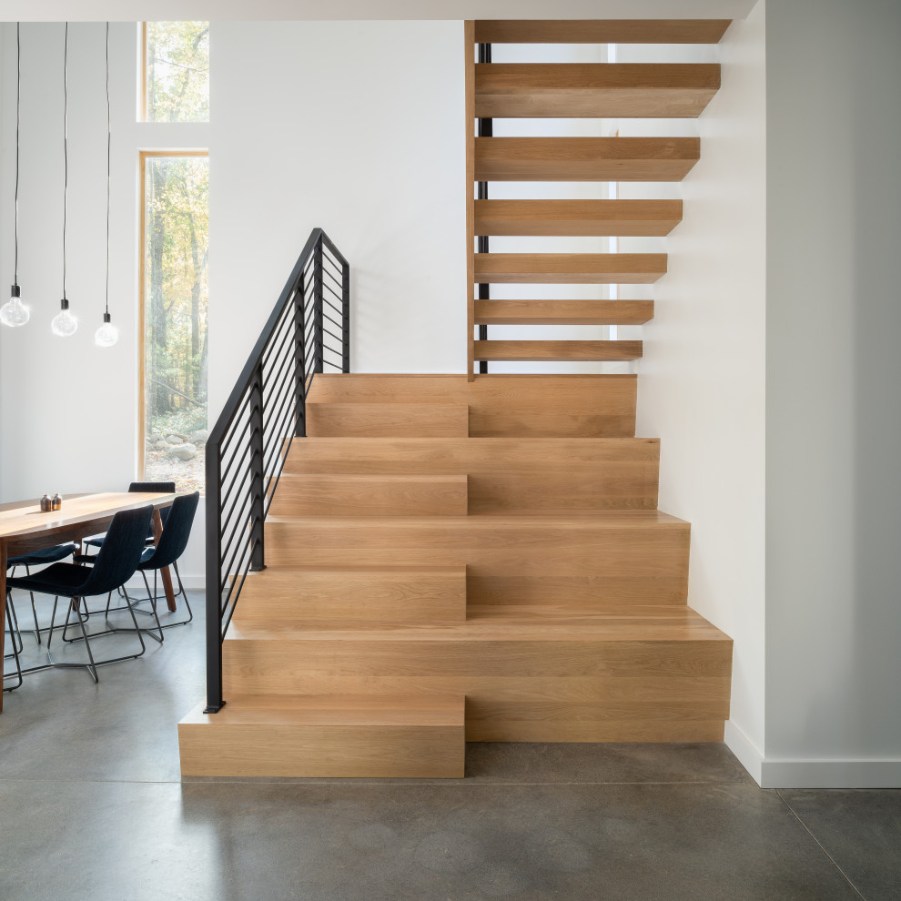 Diseño de escalera minimalista con contrahuellas de madera y barandilla de metal