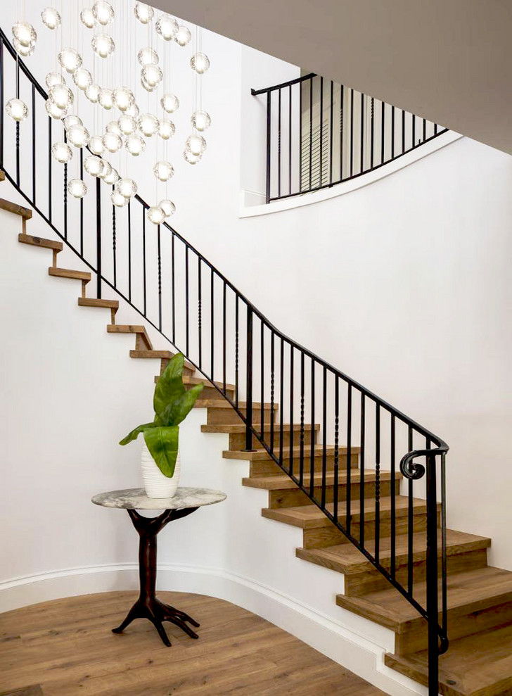 Foto de escalera curva minimalista grande con escalones de madera, contrahuellas de madera y barandilla de metal