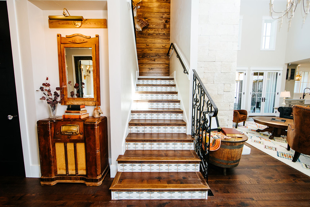 Cette image montre un escalier rustique en U avec des marches en terre cuite, des contremarches en bois, un garde-corps en métal et éclairage.