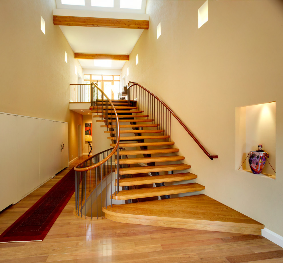 Cette photo montre un grand escalier sans contremarche courbe tendance avec des marches en bois et palier.