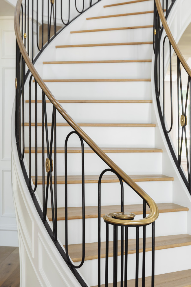 Inspiration pour un très grand escalier courbe avec des marches en bois, des contremarches en bois et un garde-corps en métal.