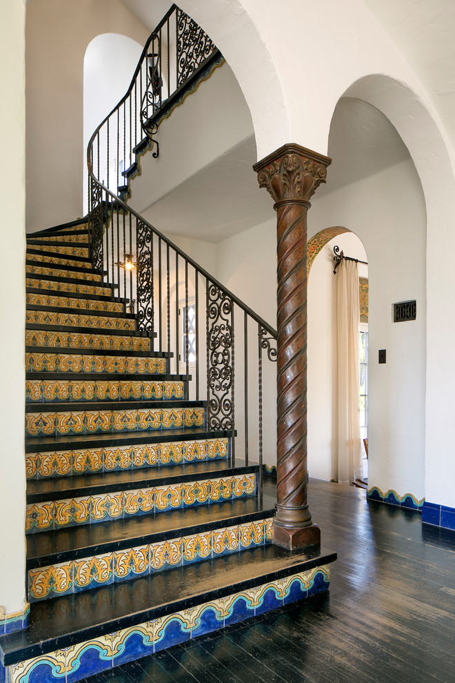 Пример оригинального дизайна: огромная изогнутая лестница в средиземноморском стиле с крашенными деревянными ступенями и подступенками из плитки