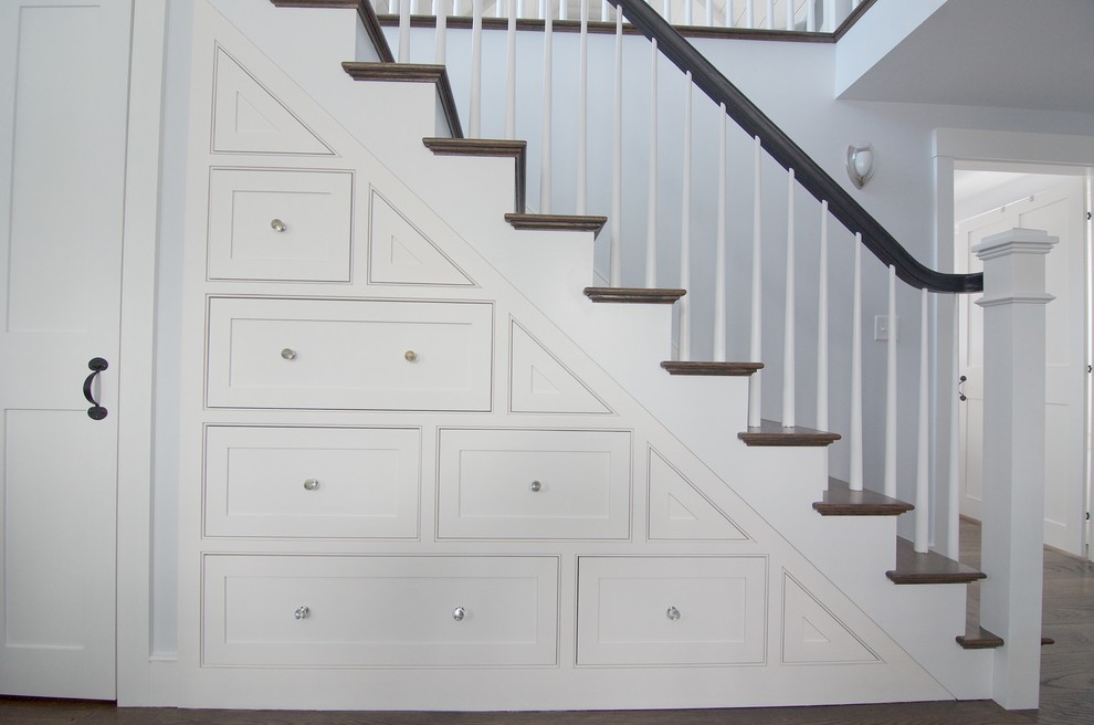 Стильный дизайн: большая прямая лестница в стиле неоклассика (современная классика) с деревянными ступенями, крашенными деревянными подступенками, деревянными перилами и кладовкой или шкафом под ней - последний тренд