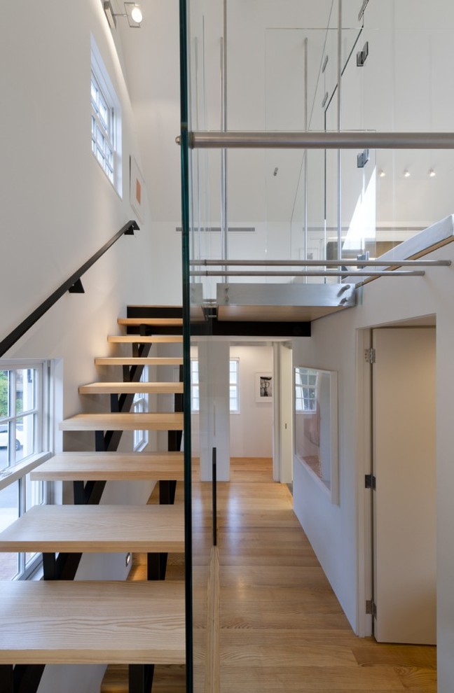 На фото: большая лестница на больцах в стиле модернизм с деревянными ступенями без подступенок
