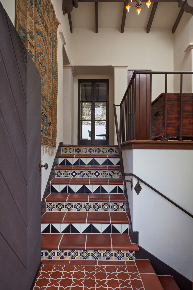 Foto de escalera mediterránea con contrahuellas con baldosas y/o azulejos, escalones de terracota y barandilla de metal