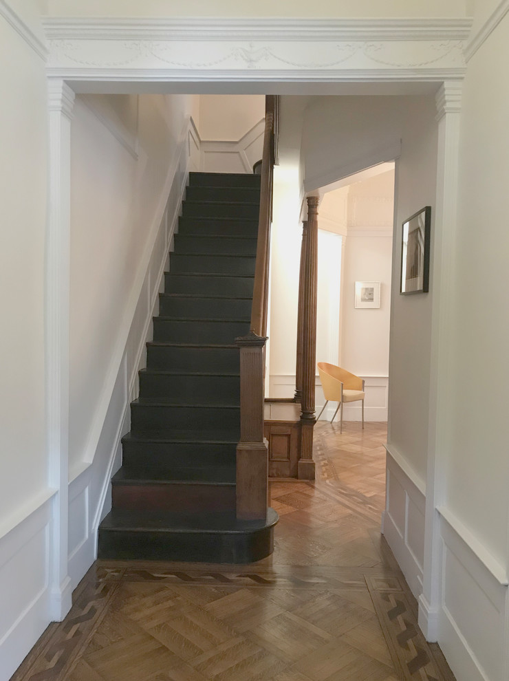 Large traditional wood straight wood railing staircase in New York with wood risers and panelled walls.