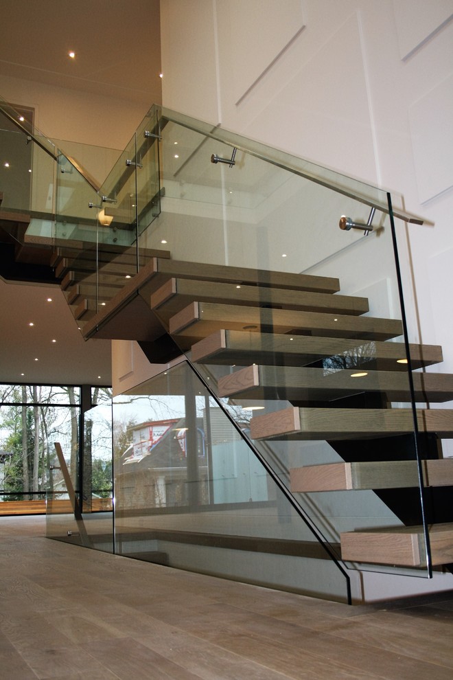 Modern inredning av en stor flytande trappa i metall, med sättsteg i metall och räcke i glas